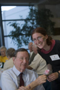 Member of the Class of 1951 holding a pink rose with another person at a forum in 2006