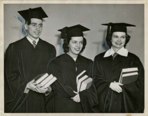Class of 1951 graduates Louis Domian, Marjorie Witherspoon, LeAnn Martin standing in caps and gowns, holdings books