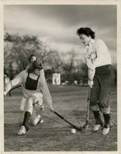 Two students in action playing field hockey