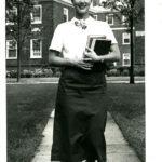 Woman with books walking on campus class of 1961