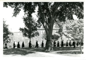 Grads walking in a line across lawn