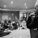 Photo of President Flemming in the foreground with a circle of seated students around him at a sit-in