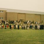Macalester graduates and family and friends on the lawn in front of the gym
