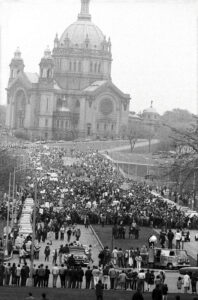 Huge crowd of people headed to the Minnesota state capitol, Spring 1970; the Cathedral can be seen in the background