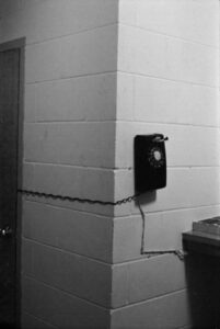Photo of a wall-mounted phone in 1966, with the cord stretched around the corner into a closet