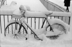 Photo of an abandoned bike, covered in snow, outside Old main, winter 1969-1970