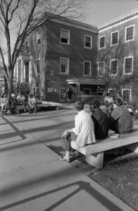 Small groups of students hanging out on benches outside of the Student Union, Fall 1966