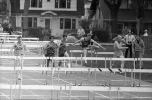 Runners jumping hurdles at a MIAC track meet in Spring 1969