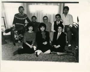 Group photo of multiple members of the Cervantes family who have attended Mac, with some sitting on the floor and the rest sitting on a couch