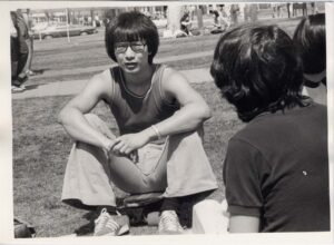 black and white photo of student sitting on a skateboard talking with friends