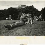 Student reclining on Shaw Field with a dog