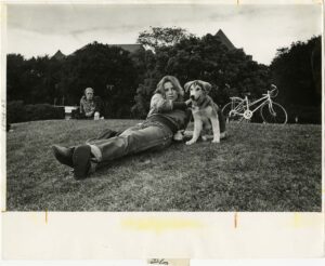 Student reclining on Shaw Field with a dog