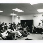 Vernon Bellecourt. standing at the front of a room, speaking to students in April 1990
