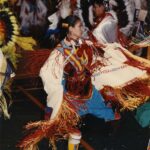 Color photo of dancers on the floor in traditional dess at a pow wow sponsored and organized by PIPE