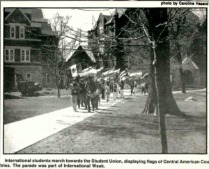 Mac Weekly 4/22/1988 photo of international students holding flags walking on the sidewalk, as part of International Week