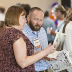 Two people looking at a publication at Reunion 2016