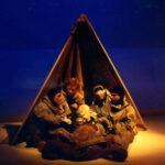 Image of four performers on stage huddled in a tent in Terra Nova 1987