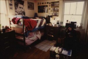 Photo of a Wallace Hall dorm room, 1/24/1991, showing bunk beds, dressers, and various posters on the wall