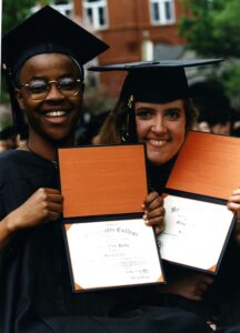 Two students in caps and gowns, showing off their diplomas, at Commencement 1996