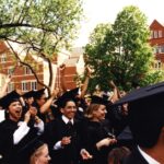 Group of smiling graduates in caps and gowns in front of Old Main at Commencement 1996
