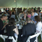 Members of the Class of 1996 eating at tables under a big tent at Reunion 2006