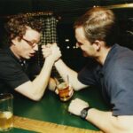 Two people arm wrestling at a table during the Class of 1996 gathering at O'Gara's at Reunion 2001