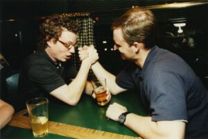 Two people arm wrestling at a table during the Class of 1996 gathering at O'Gara's at Reunion 2001