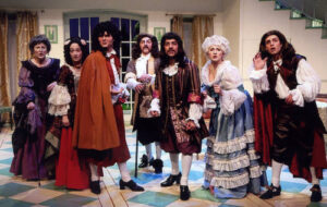 An image from the 2009 production of the Tartuffe. Seven characters are looking straight forward with various looks of distress.