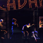 An image from the 2010 production of Cabaret. Five characters in dark lighting, dancing.