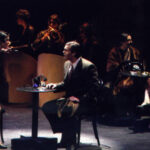 An image from the 2010 production of Cabaret. Two characters are at a table arguing.