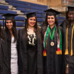 Five females in their cap and gown during commencement