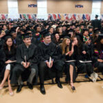 Mac students siting in the field house in their caps and gowns during Commencement