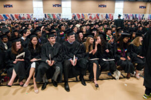 Mac students siting in the field house in their caps and gowns during Commencement