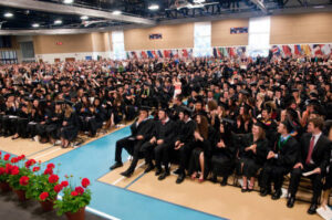 A wide image of the two sections of mac students sitting in the field house during commencement