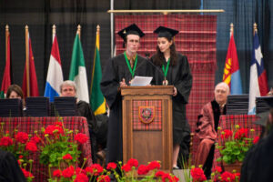 Two Mac students at a pedestal giving a speech during commencement.