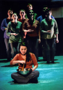 Scene: performer sitting on floor stirring a bowl