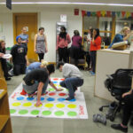 Students playing Twister while others look on